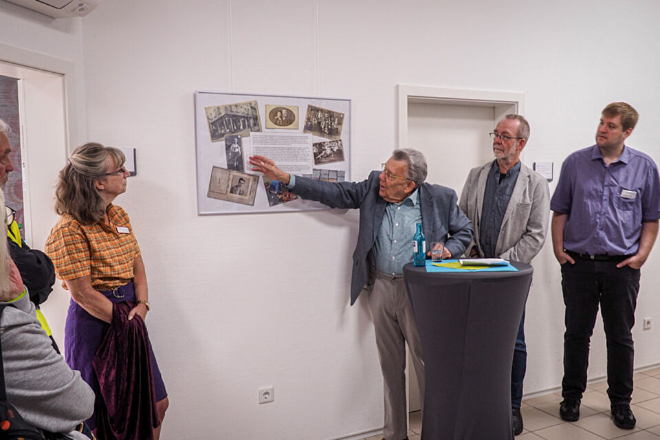 Mann erklärt die Bilder einer Gedenktafel.
