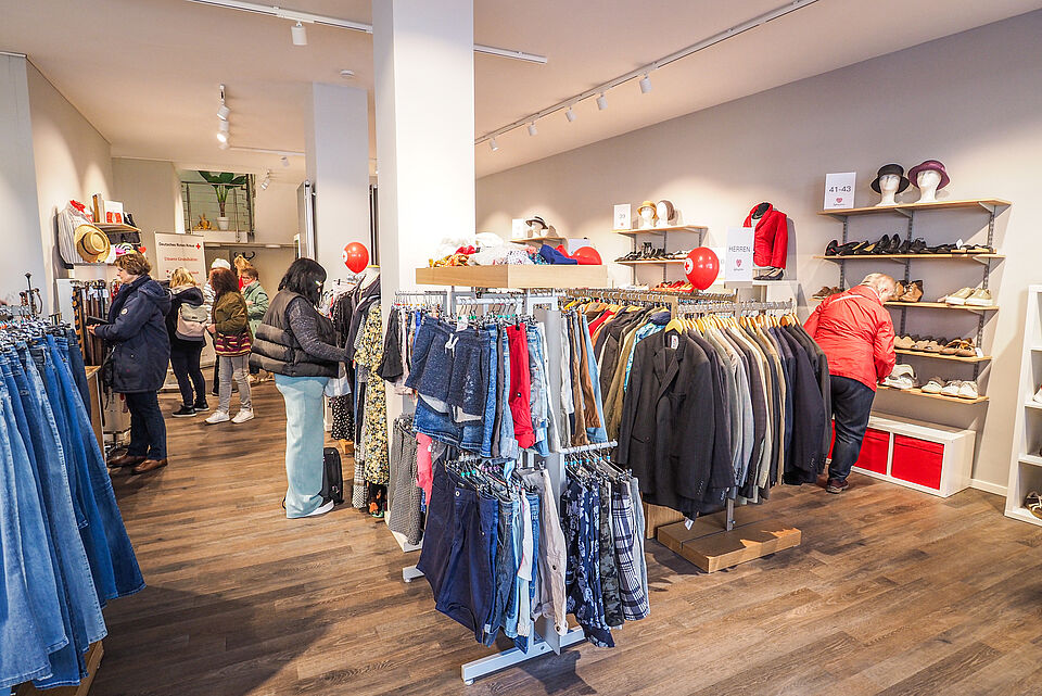 Blick in den Kleidershop mit Kleiderständern und Kunden.