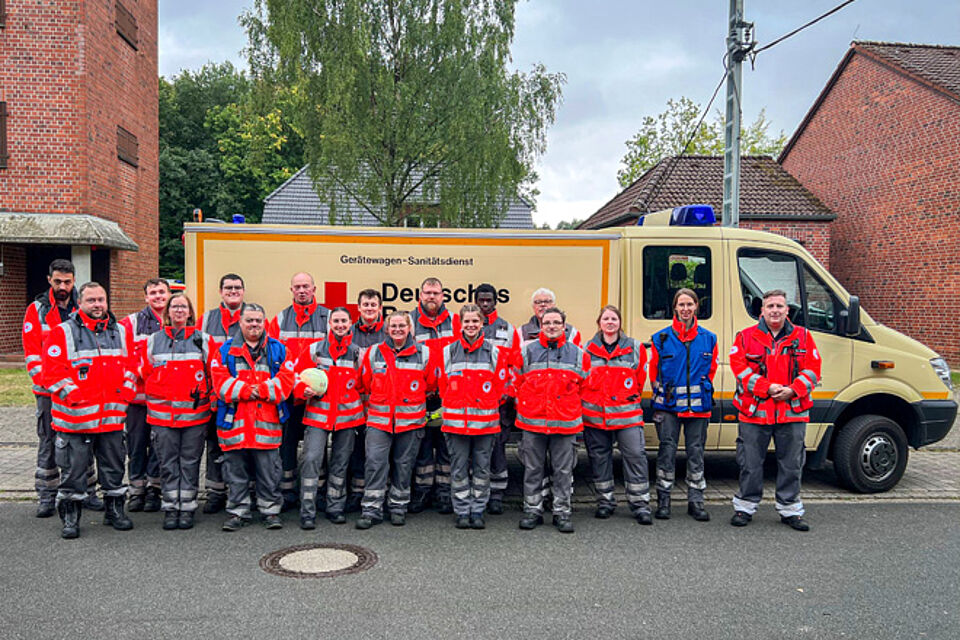 Eine Gruppe von 18 DRK-Helferinnen und -helfern steht vor einem Gerätewagen des DRK Bochum.
