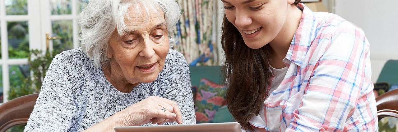 Junge Dame erklärt älterer Dame ein Tablet