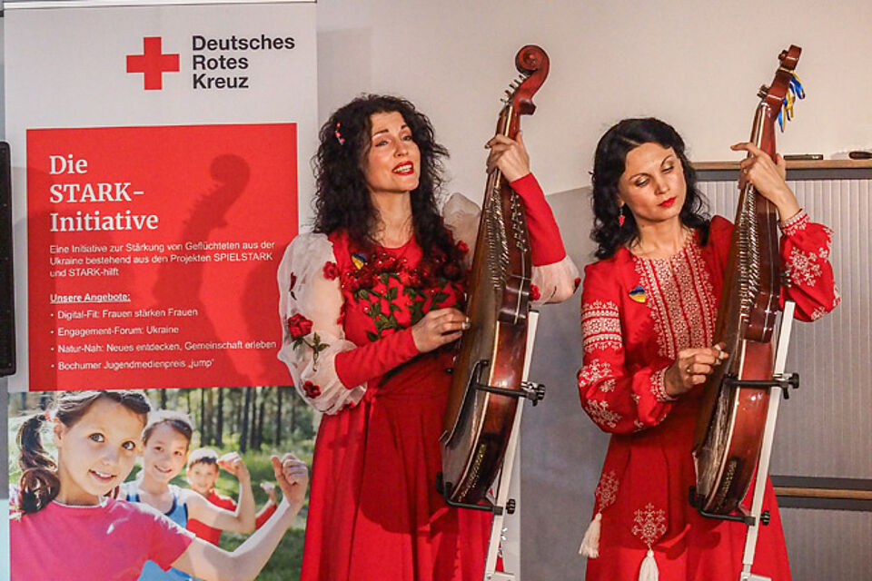 Zwei Frauen in ukrainischer Tracht spielen eine Bandura.