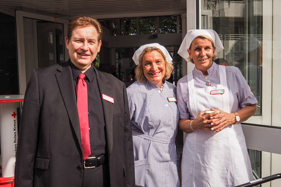 Mann mit zwei Frauen in Schwesterntracht.