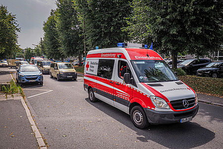 DRK-Fahrzeugkolonne rückt mit Blaulicht aus, vorne der Wagen der Einsatzleitung.