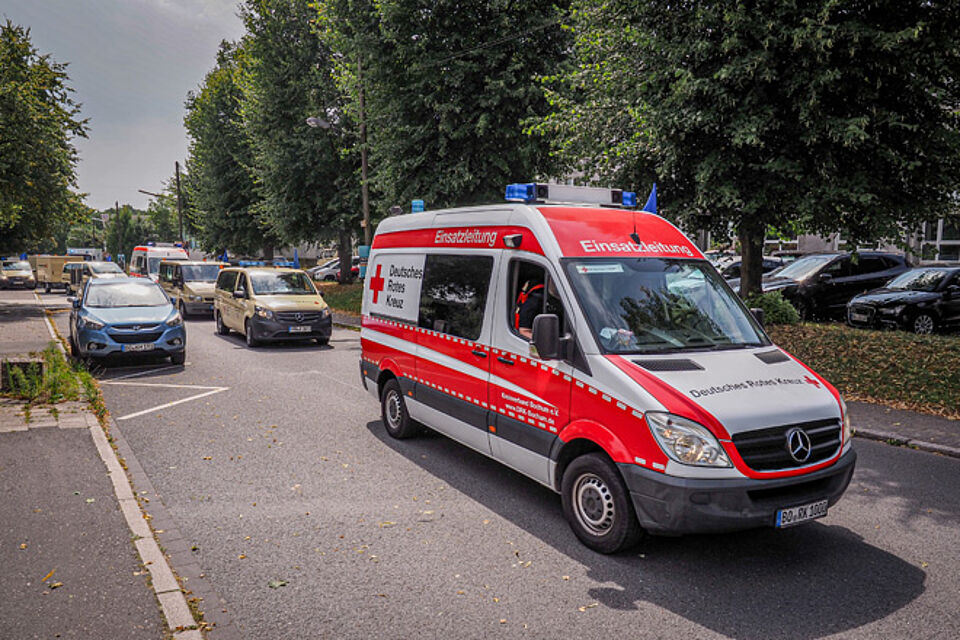DRK-Fahrzeugkolonne rückt mit Blaulicht aus, vorne der Wagen der Einsatzleitung.