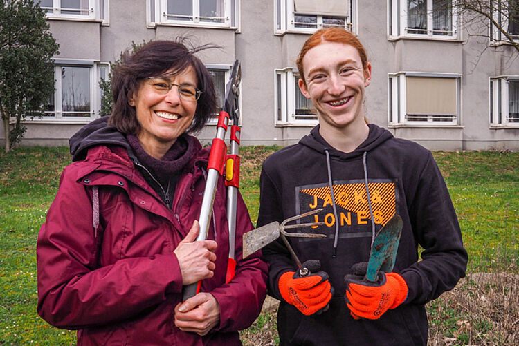Frau und Junge mit Gartengeräten.