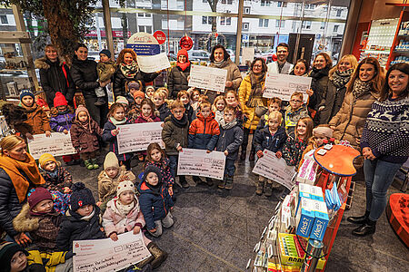 Kinder halten Schecks hoch.