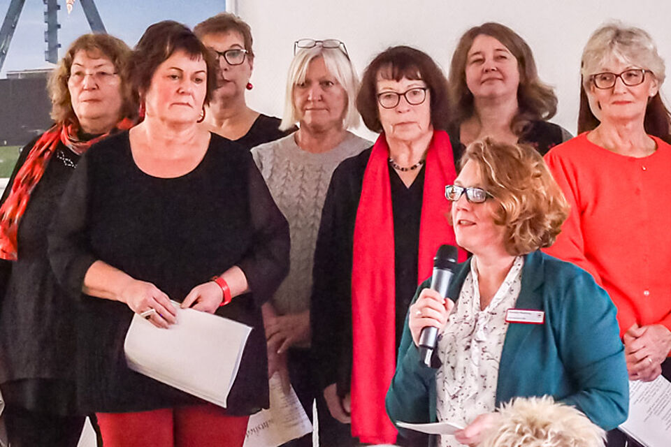 Frau mit Mikrofon vor einer Gruppe Frauen