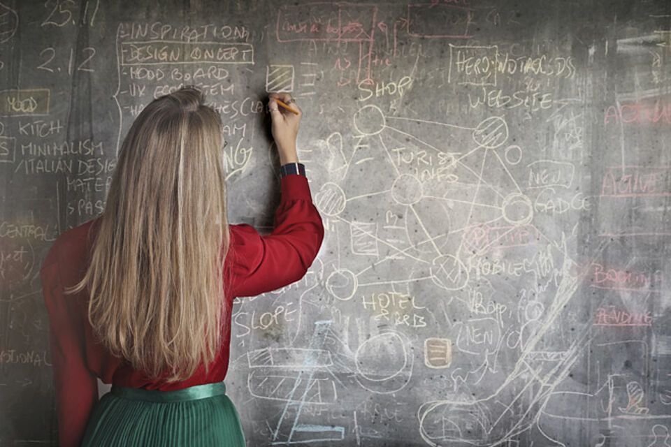 Lehrerin schreibt komplizierte Formeln an eine Tafel