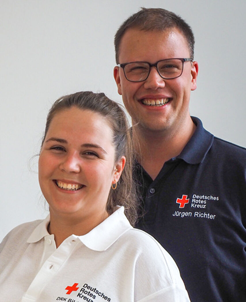 Ansprechpartner Bildungszentrum Eine Frau in weißem DRK-Shirt und ein Mann in blauem DRK-Shirt lächeln.