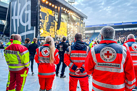 Sanitäter stehen am Rand eines Grönemeyer-Konzertes und beobachten die Menge.