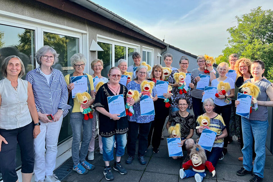 Eine Gruppe Menschen mit Handpuppen blicken in die Kamera