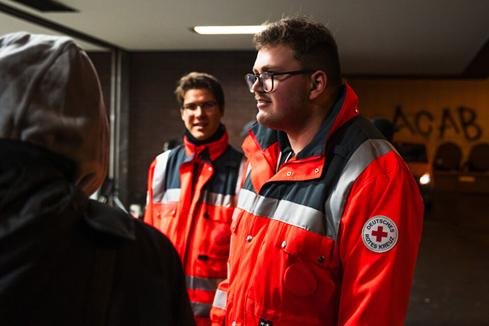Zwei Männer in Rot-Kreuz-Jacken.