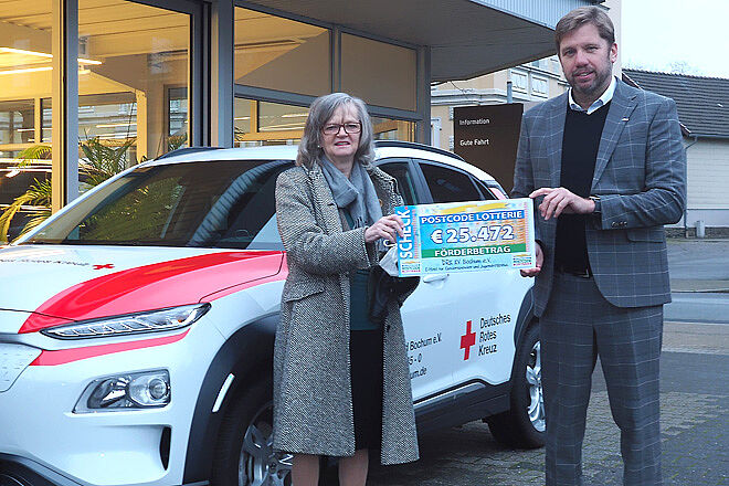 DRK-Kreisverbands-Präsidentin Dr. Ottilie Scholz und Vorstand Holger Boehnert mit dem Scheck der Deutschen Postcode Lotterie vor dem neuen Elektroauto.