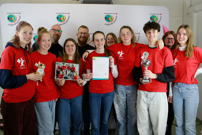 In rot gekleidete Schülerinnen und Schüler mit Urkunden und Pokal.