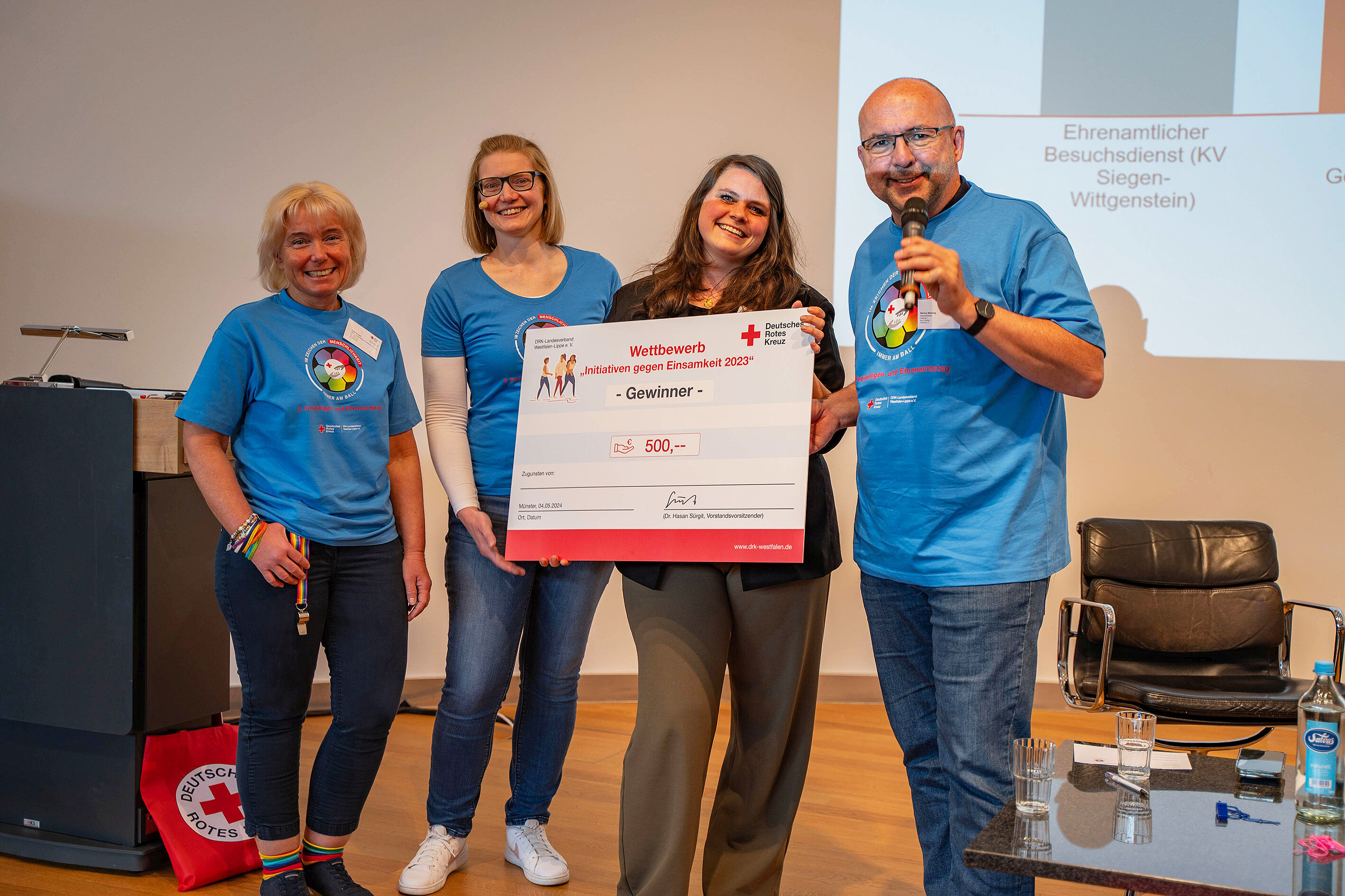 Vier Menschen halten einen großen Scheck hoch.