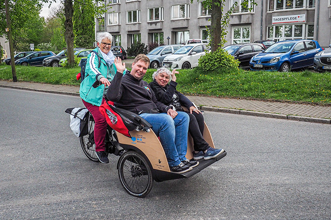 Zwei Menschen werden in einer Fahrrad-Rikscha gefahren.