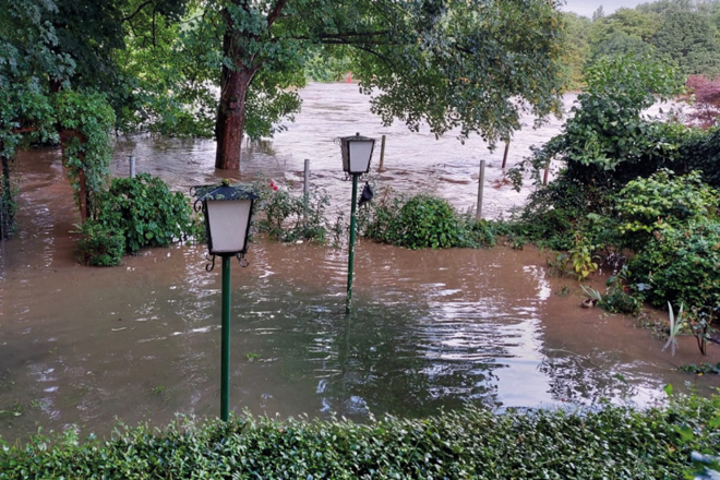 Ein Biergarten steht unter Wasser, Laternen ragen heraus.