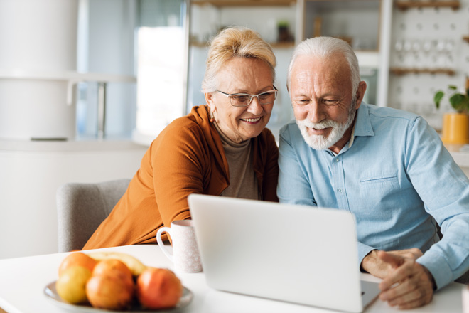 Zwei Senioren sitzen an einem Laptop.