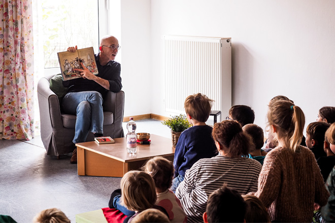 Mann zeigt Kindern ein Buch mit Bildern, aus dem er vorgelesen hat.