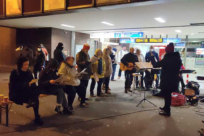 Menschen singen vor dem Hintereingang des Bochumer Hauptbahnhofs.