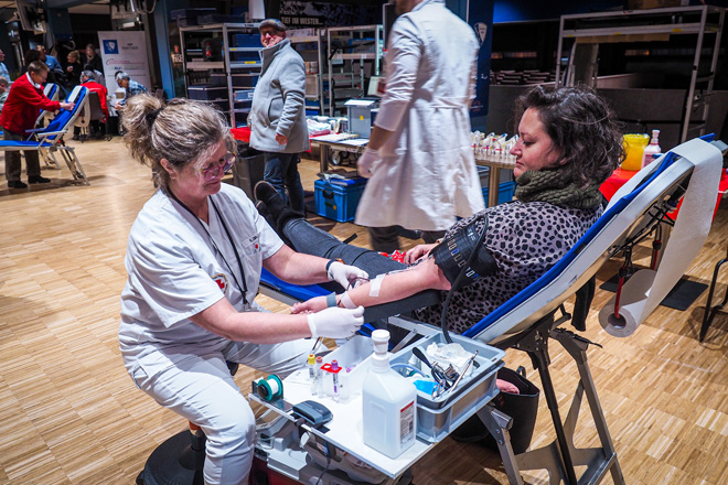 Eine Frau spendet Blut im Beisein einer Rotkreuz-Schwester.