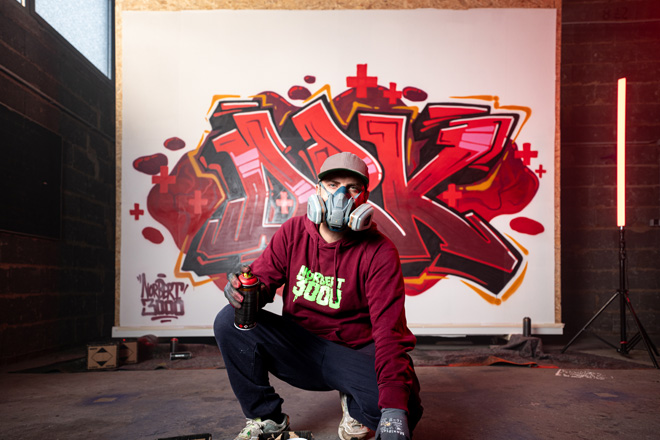 Mann mit Atemschutzmaske hat ein DRK-Graffiti erstellt.