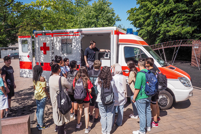 Zahlreiche Schüler betrachten einen Rettungswagen.