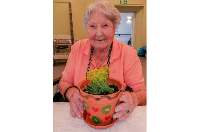 Seniorin mit selbst gestaltetem und bepflanztemTontopf