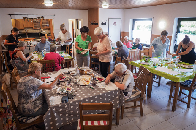 Blick in einen Raum mit malenden älteren Menschen an Tischen.
