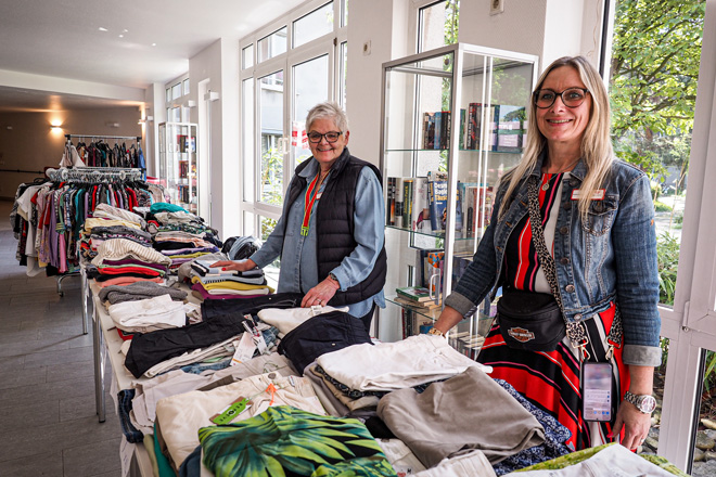 Zwei Frauen stehen hinter einem Tisch mit Kleidung.